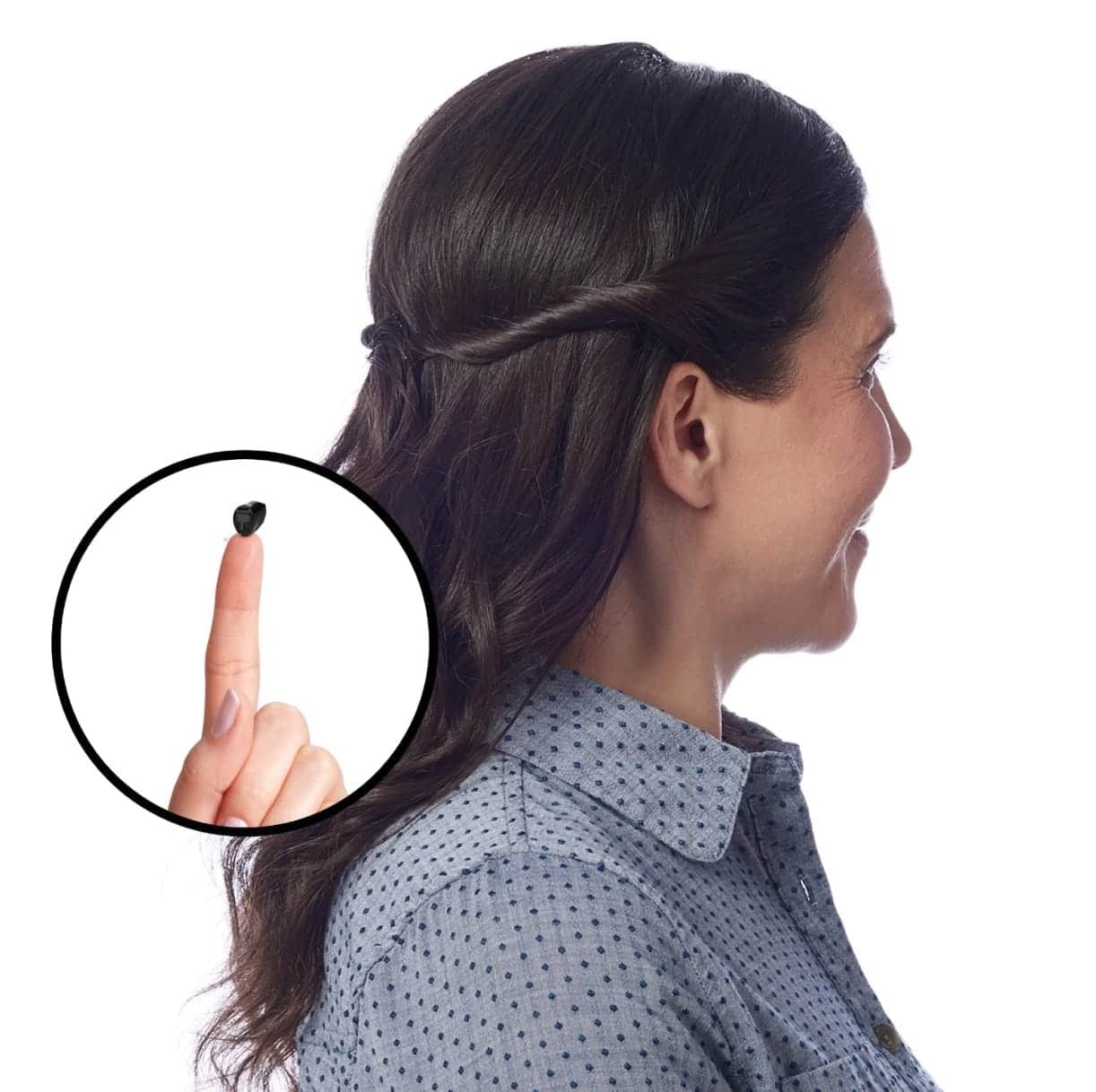A tiny invisible-in-canal hearing aid balanced on a fingertip, next to a woman's ear