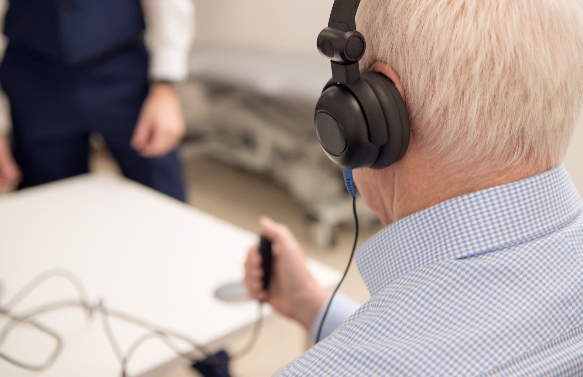 Patient wearing audiometry headphones and holding a response button during a pure-tone hearing test