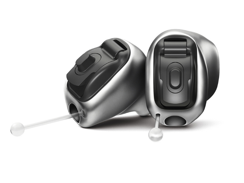 A pair of modern invisible-in-canal hearing aids with removal handles