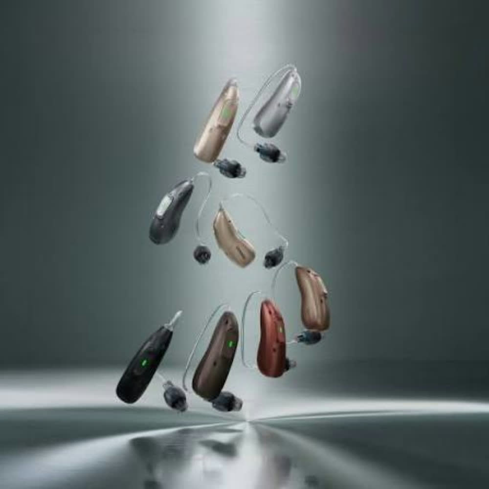 The Phonak Eon hearing aid colour range: eight receiver-in-canal devices arranged in a circle in black, grey, silver, champagne, beige, copper, red and chestnut finishes